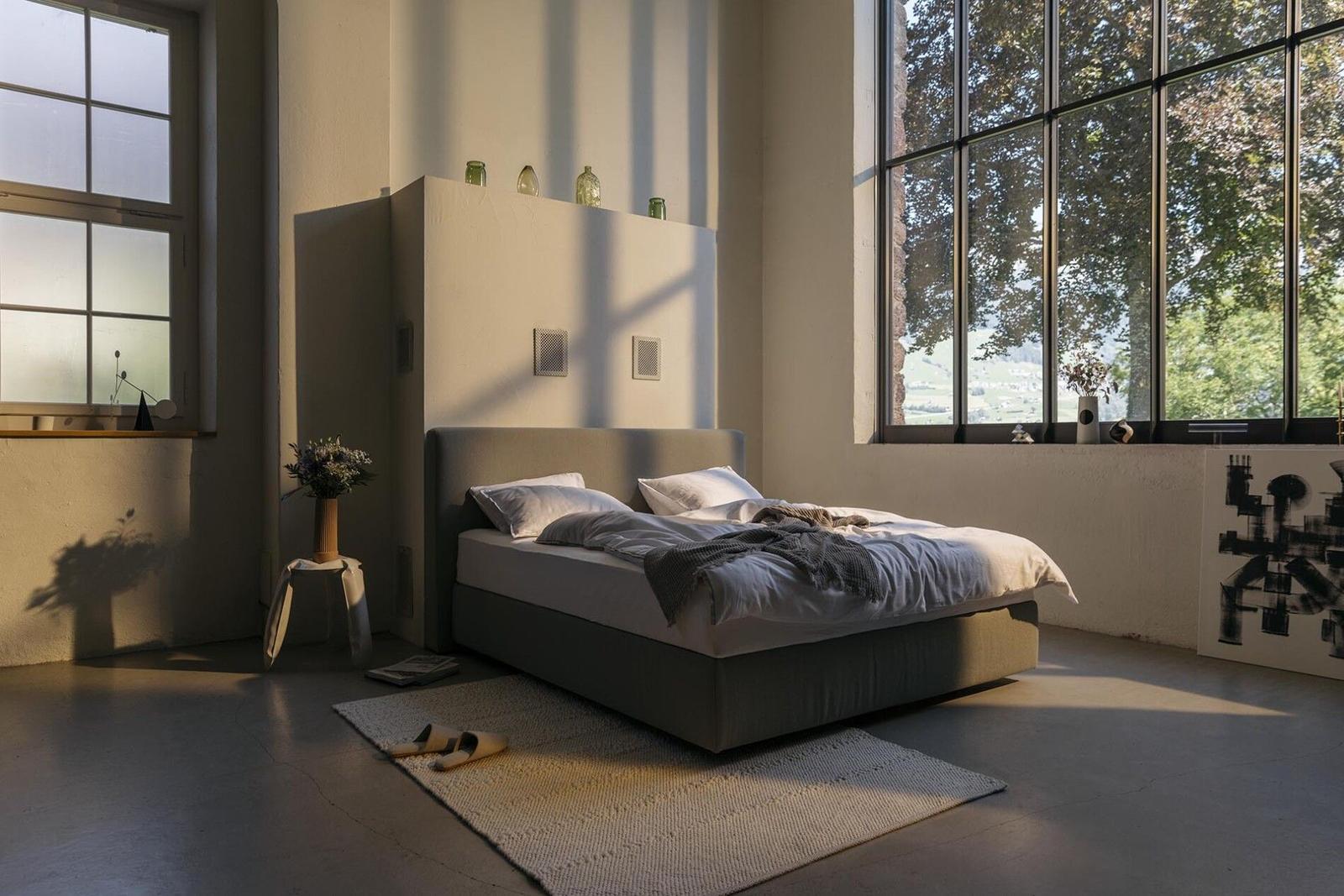 Hüsler Nest Polsterbett in einem Loft mit großen Fenstern